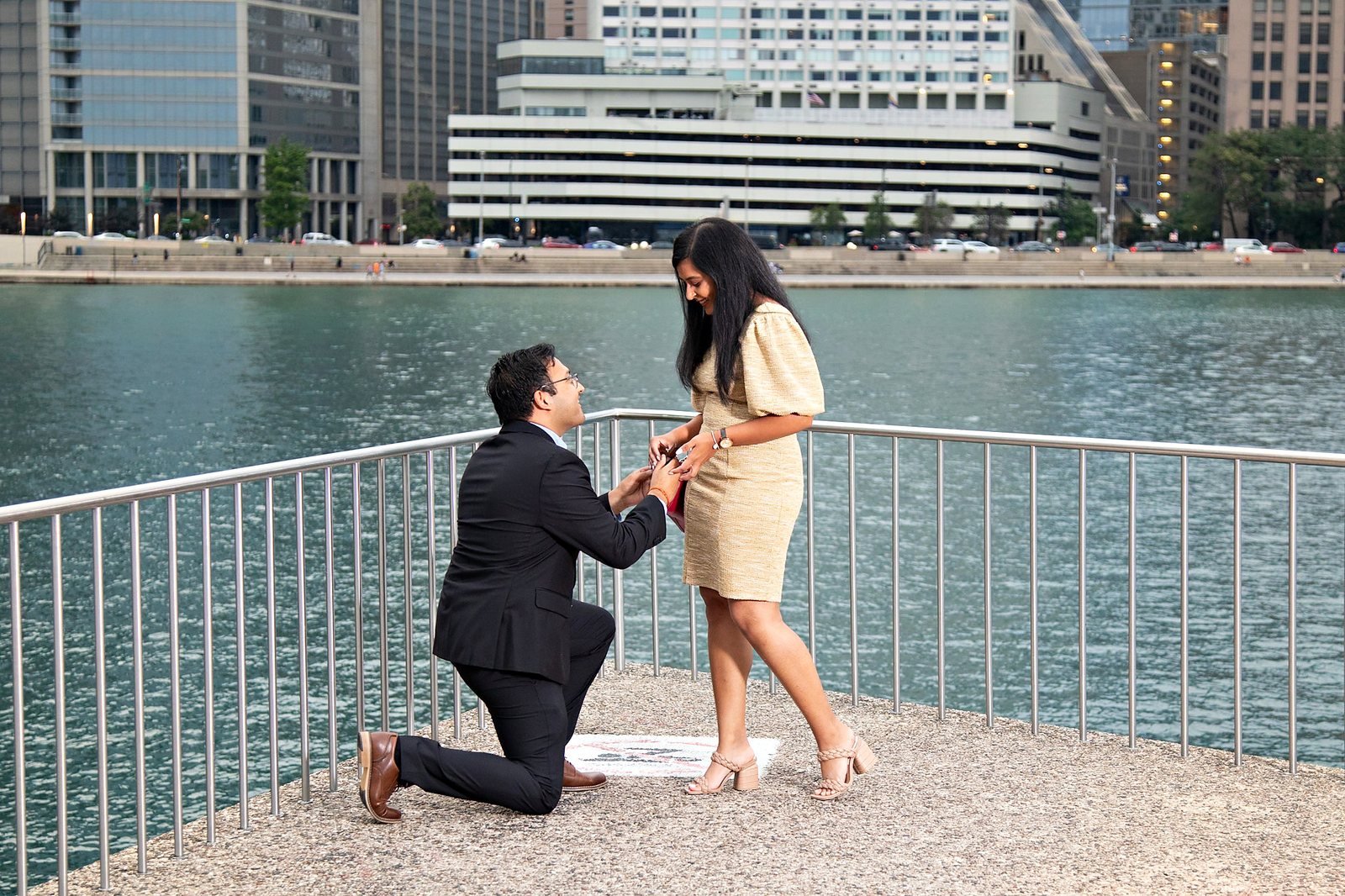 Surprise marriage proposal on one knee at the Chicago Riverwalk during a golden sunset, by The Love Pics