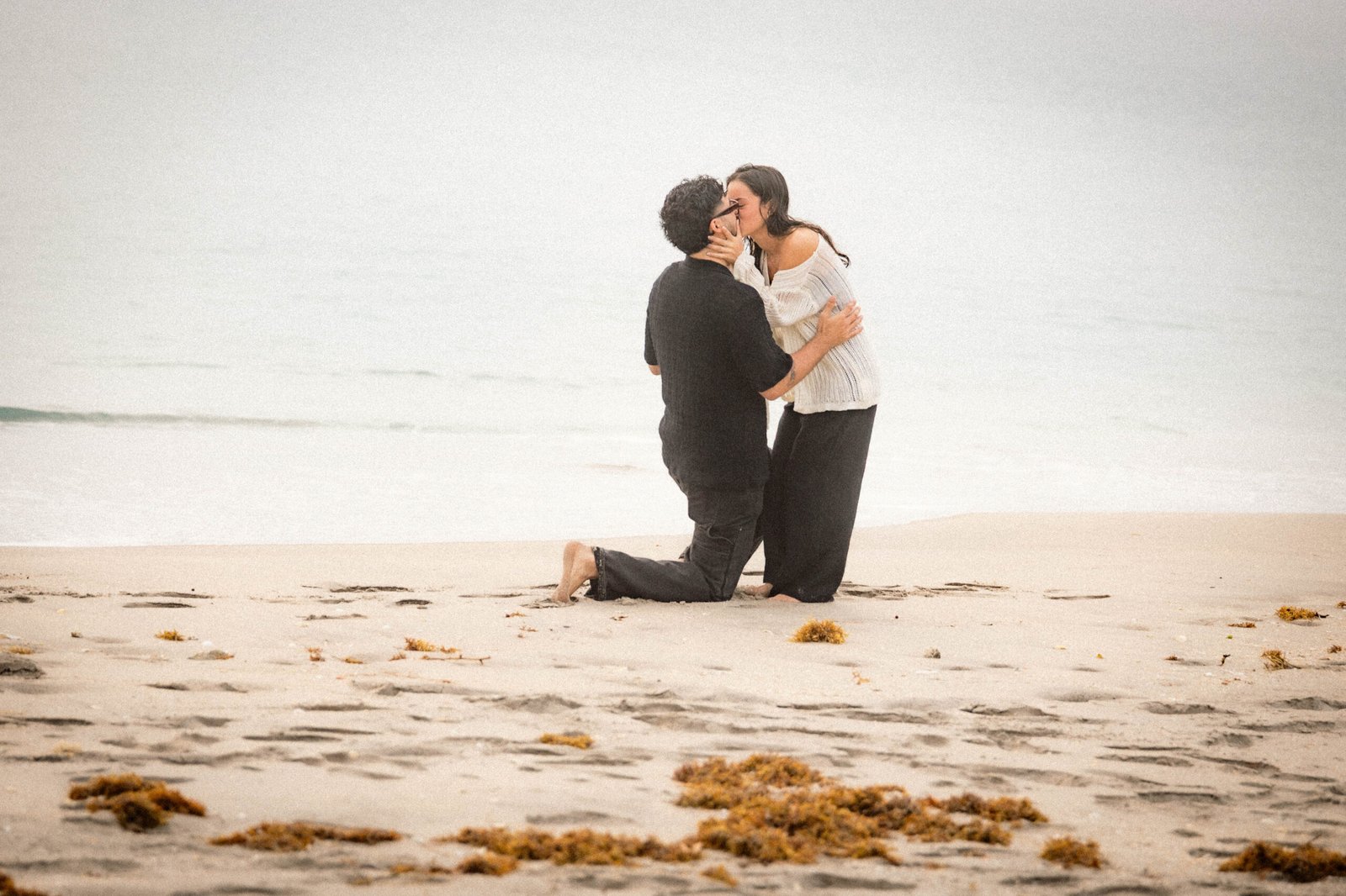 Couple kissing after beach proposal man kneeling West Palm Beach engagement photographer she said yes