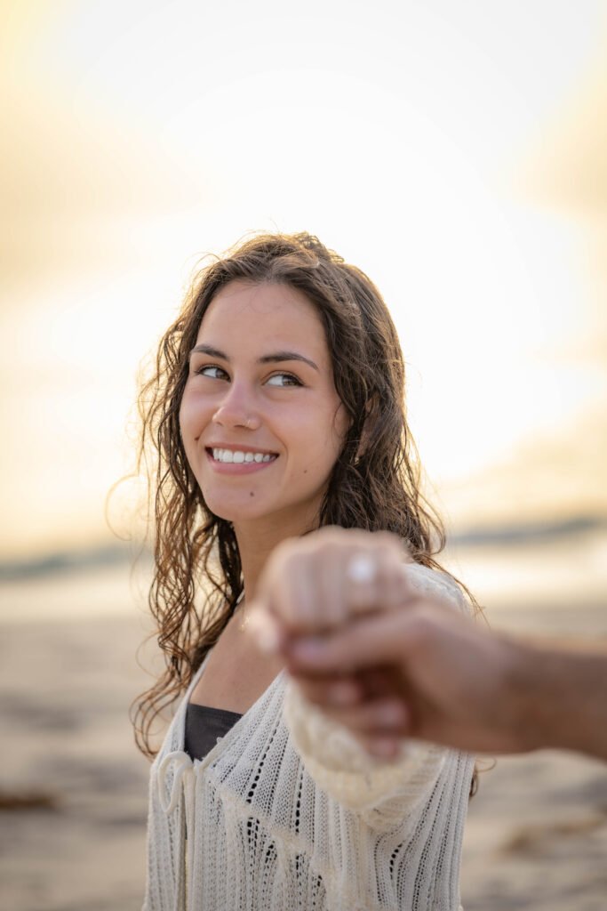 Woman smiling reaching toward camera during West Palm Beach engagement photo session on the beach