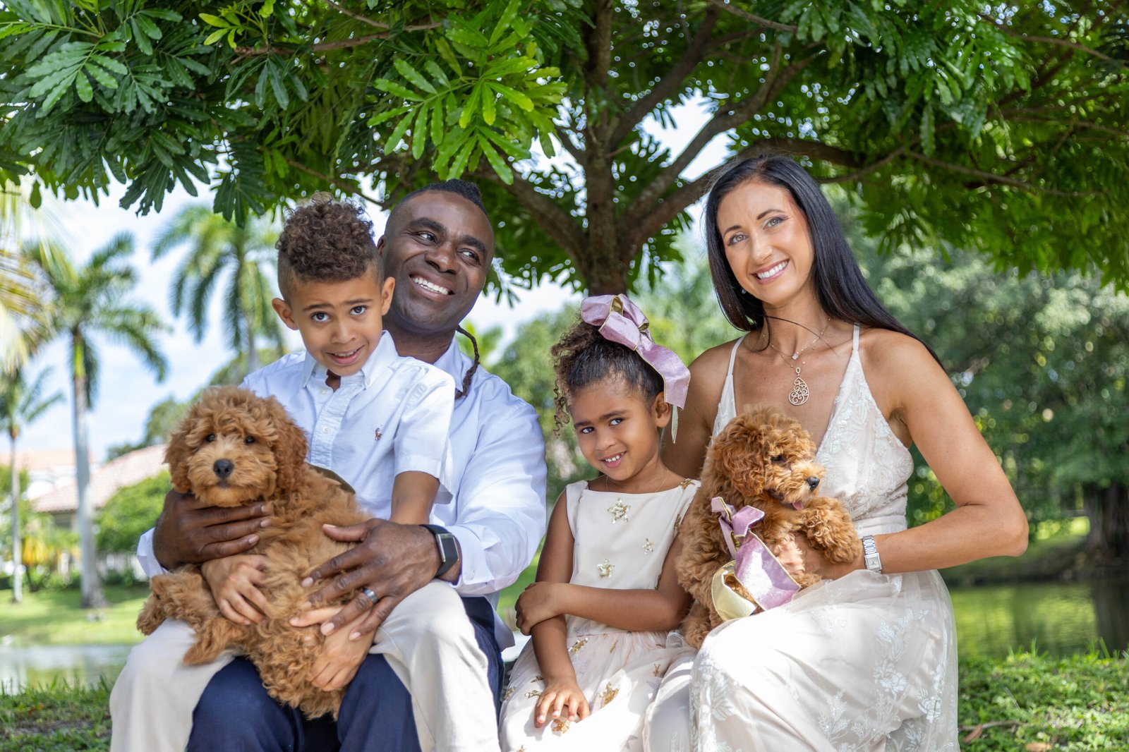 Happy family with two children and their labradoodle dogs in a portrait session under a leafy tree