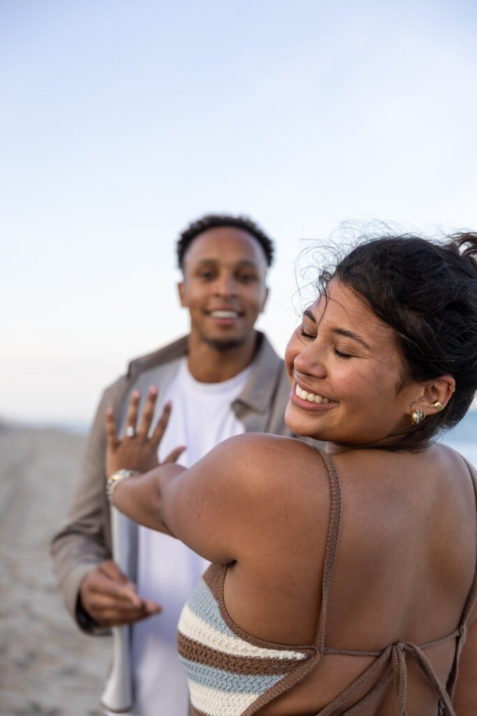 Woman showing engagement ring smiling with fiance behind West Palm Beach engagement photographer