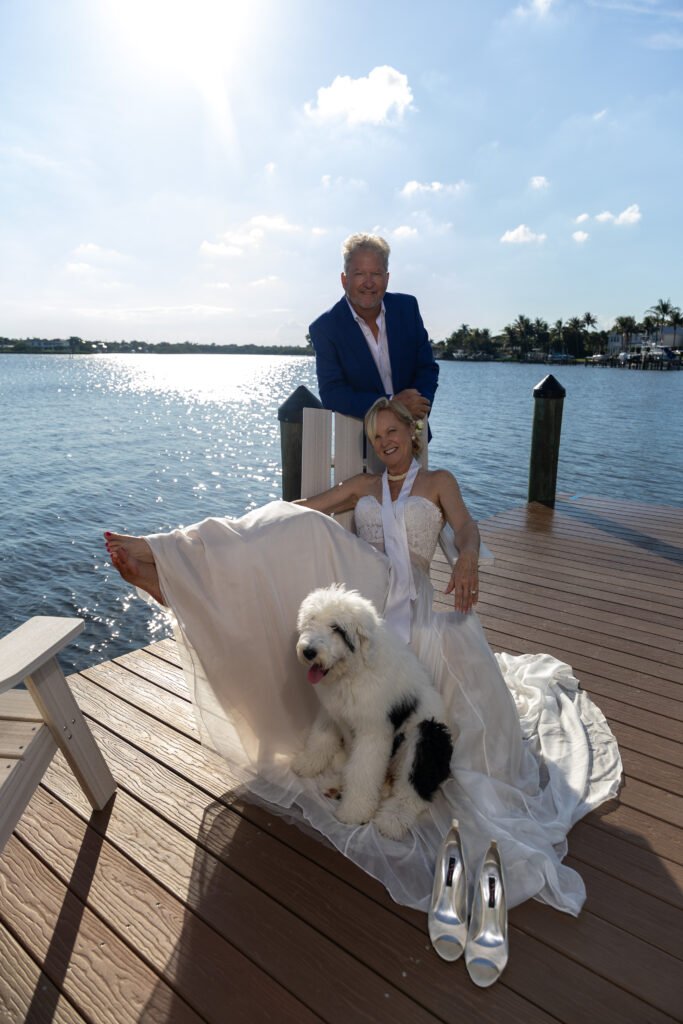 Elegant couple with white dogs on dock waterfront West Palm Beach engagement photography session