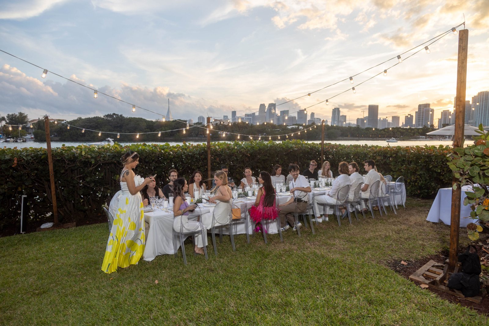Group of guests dressed in white at a golden-hour dinner celebration in Miami