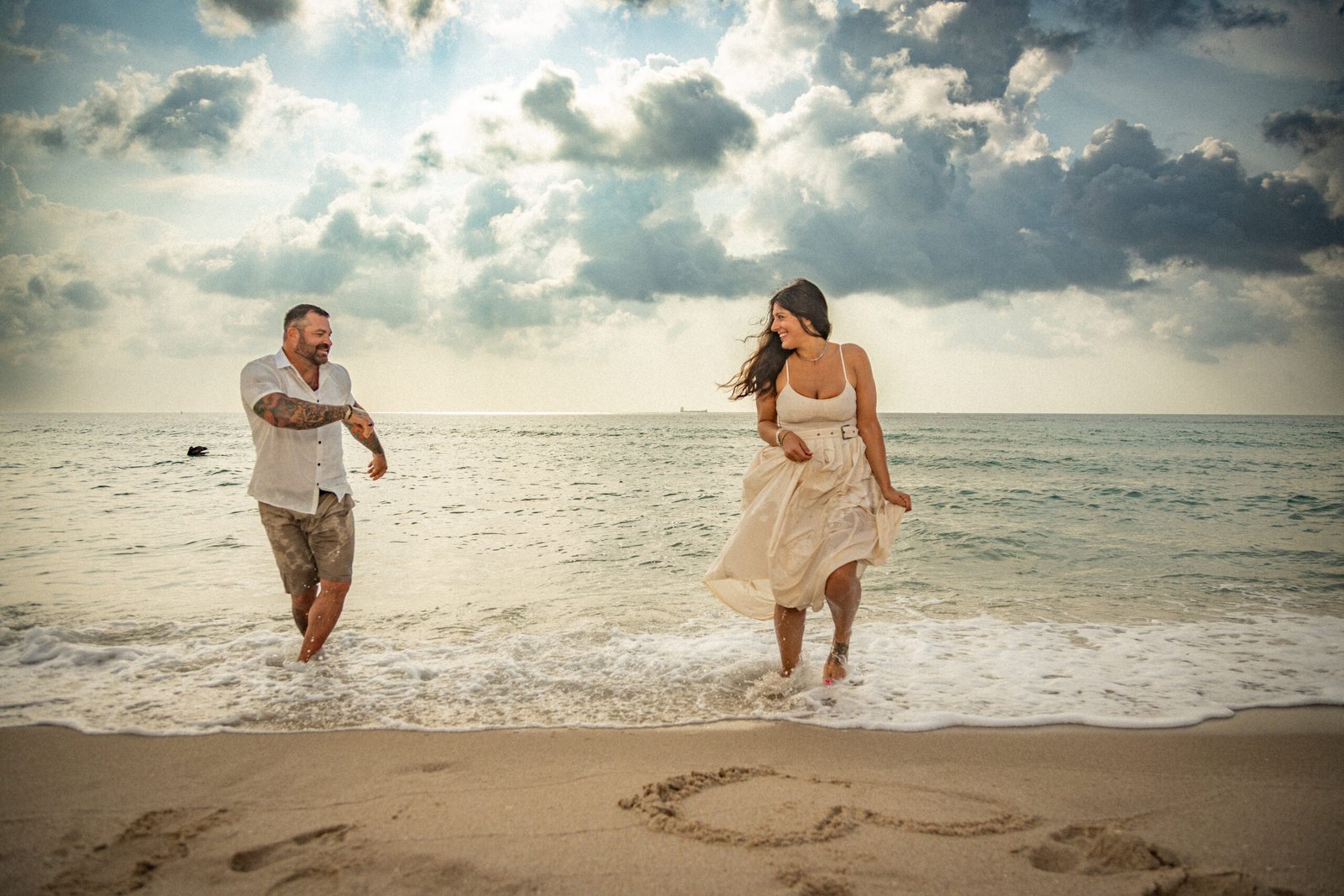Happy couple running together on the beach at sunset West Palm Beach wedding and engagement photographer