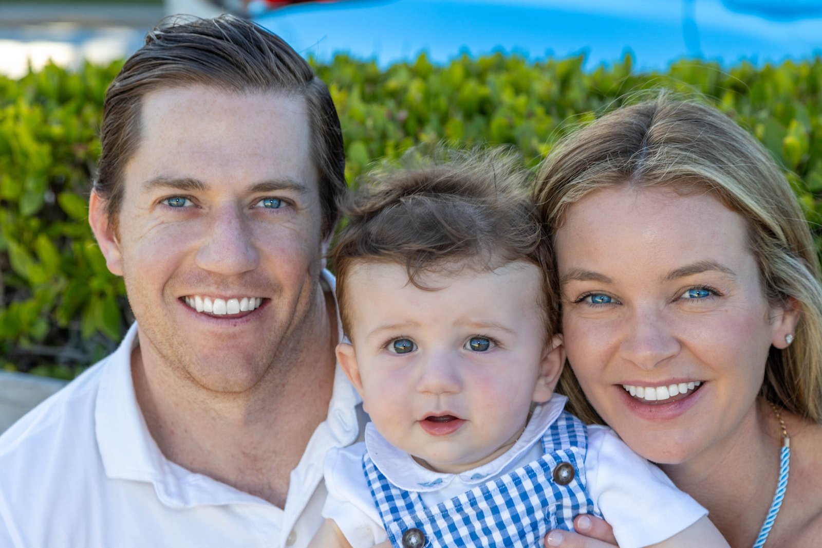 Smiling parents holding their baby boy at golden hour during a West Palm Beach family session