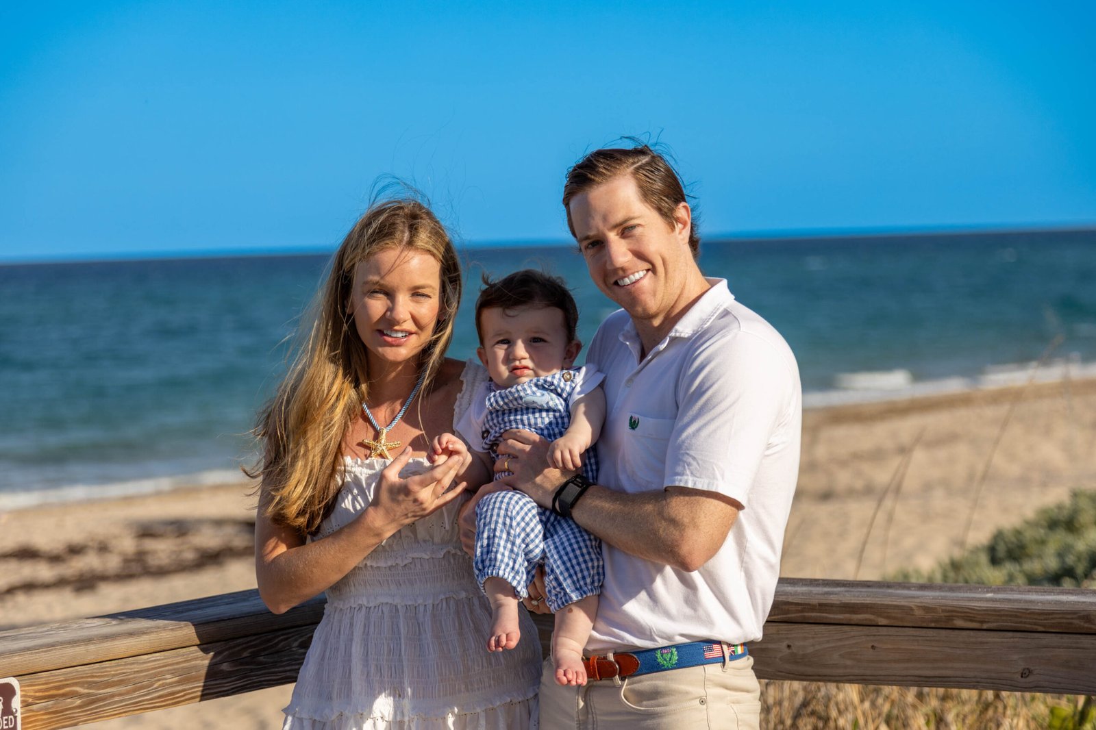 Parents holding their baby on the sand at sunset during a West Palm Beach beach family session