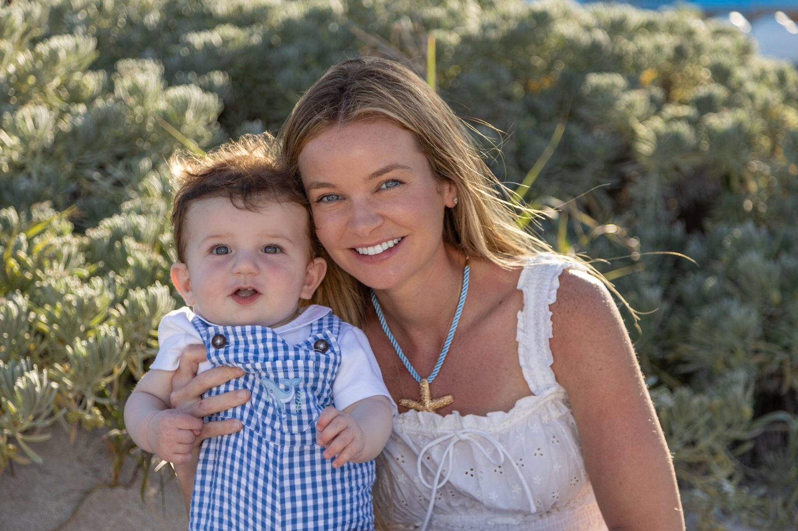 Mother cradling her baby in the beach dunes at golden hour in West Palm Beach