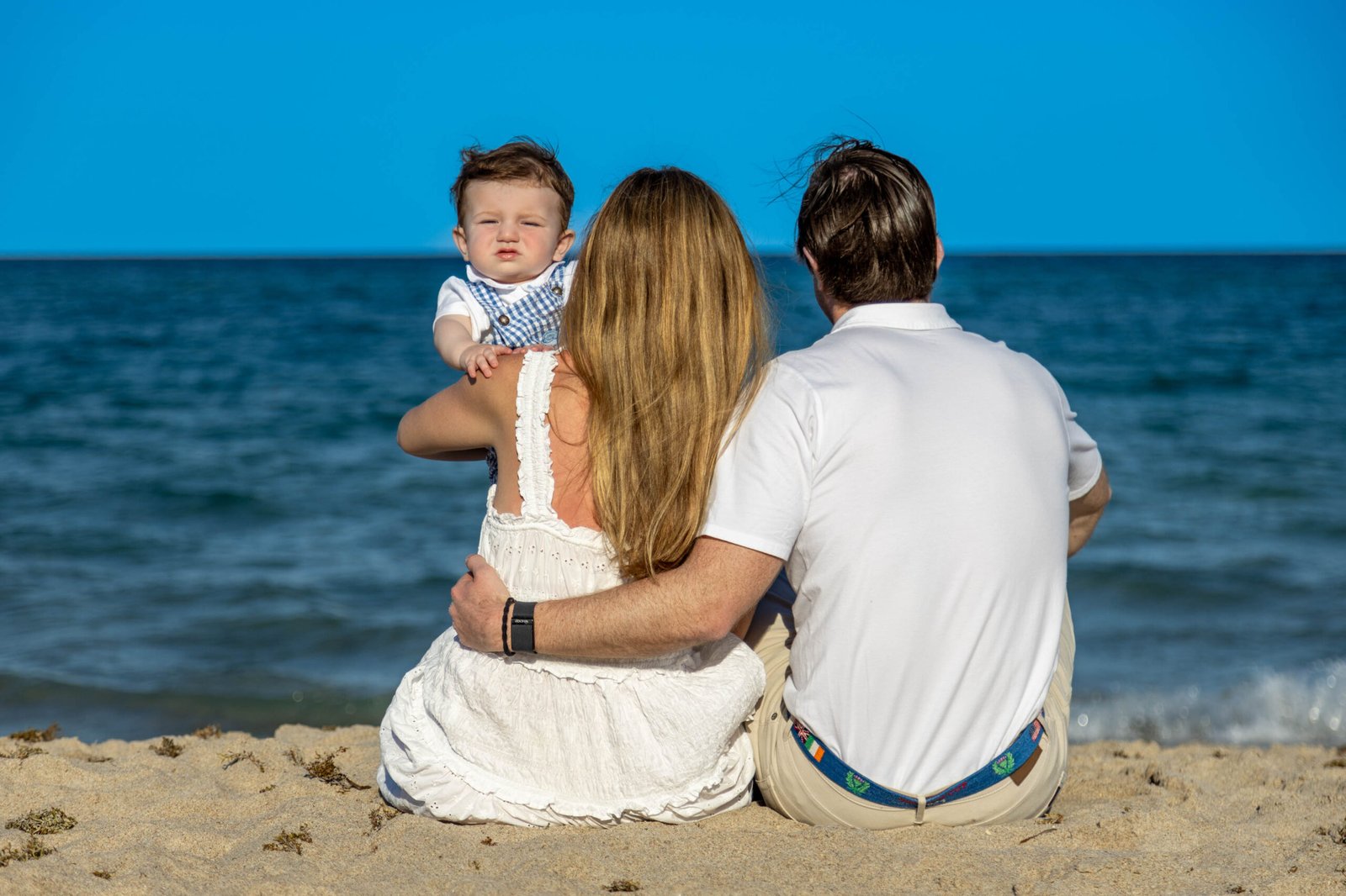 Family in white and neutral outfits watching the ocean during a West Palm Beach session