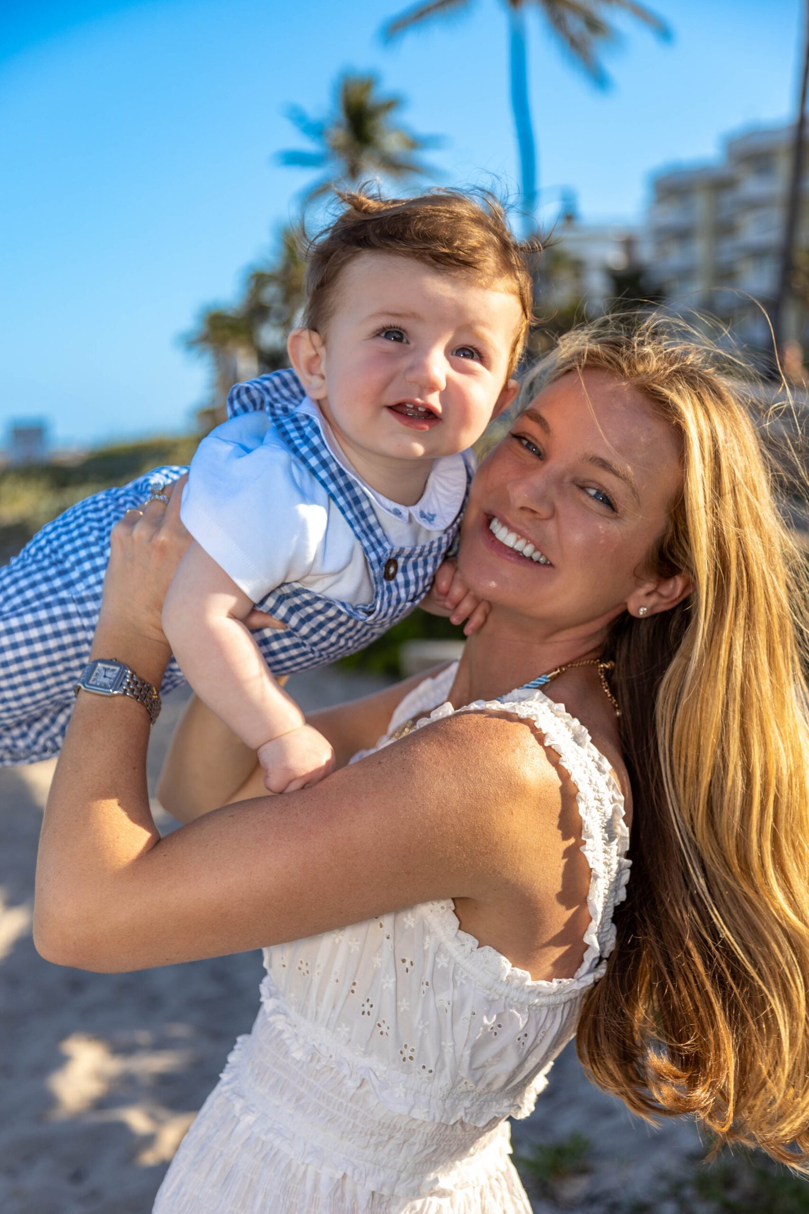 Mother carrying her son on her shoulders on the beach at sunset in West Palm Beach