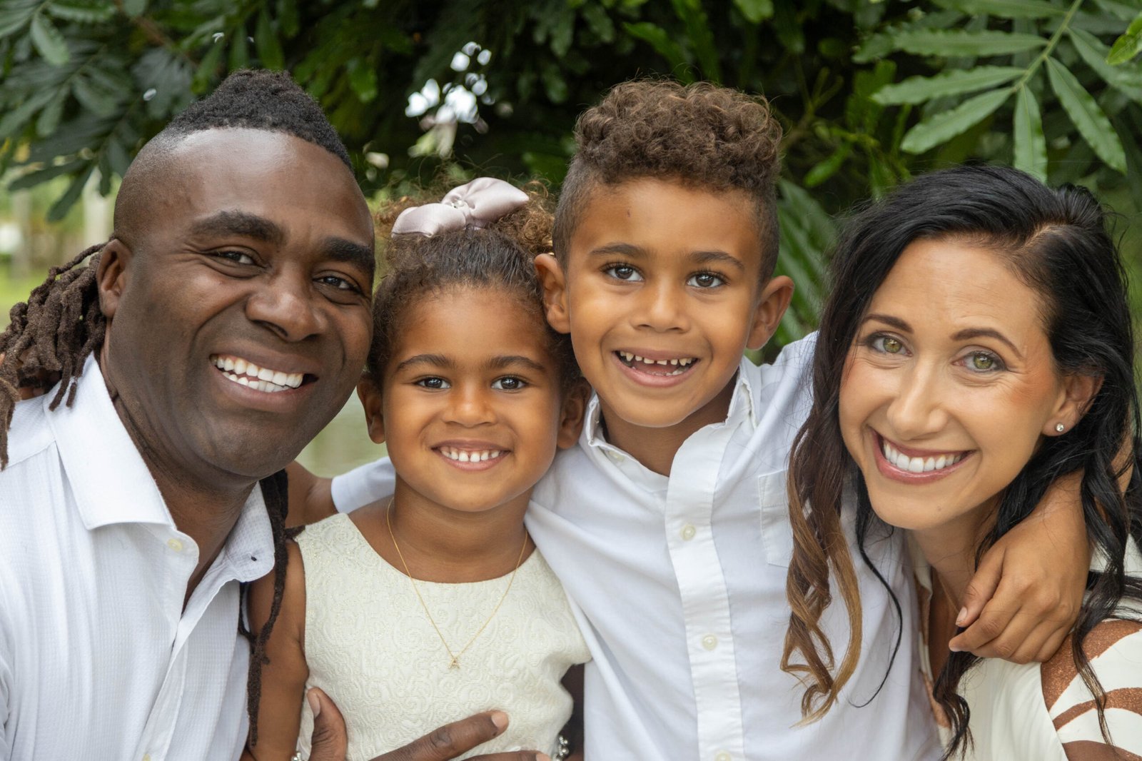 Family of four with two children in a green park during a Palm Beach County family session