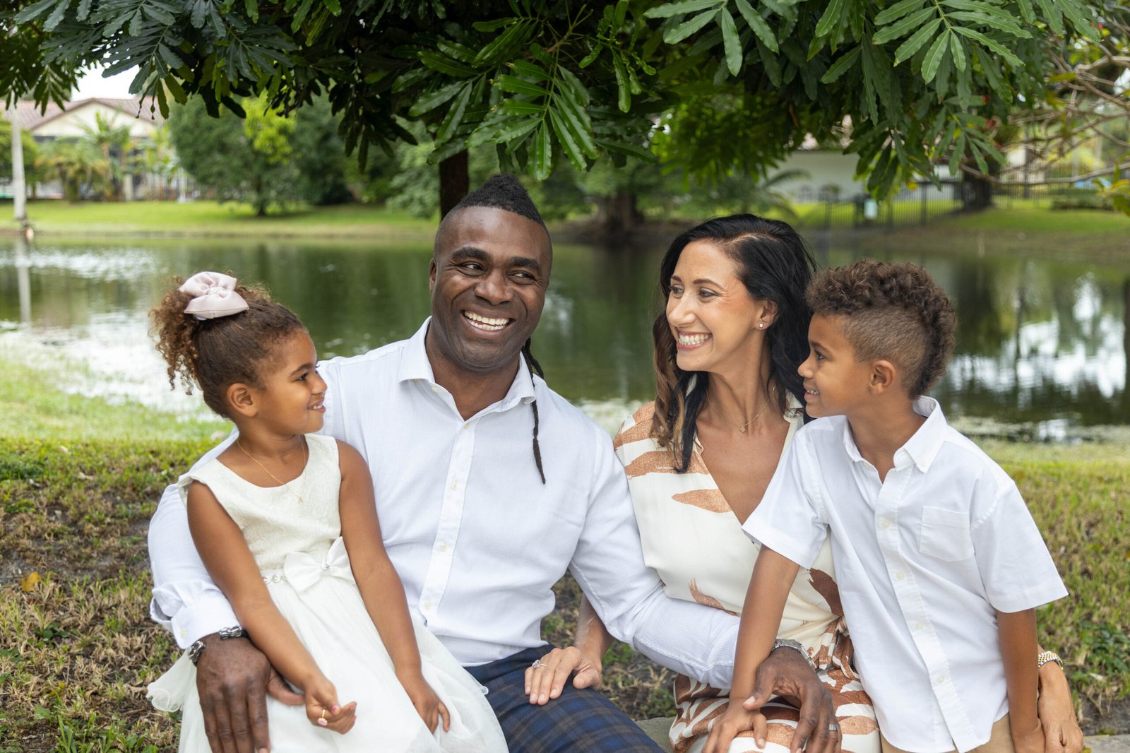 Family of four posing by the lake during a family photo session in Palm Beach County