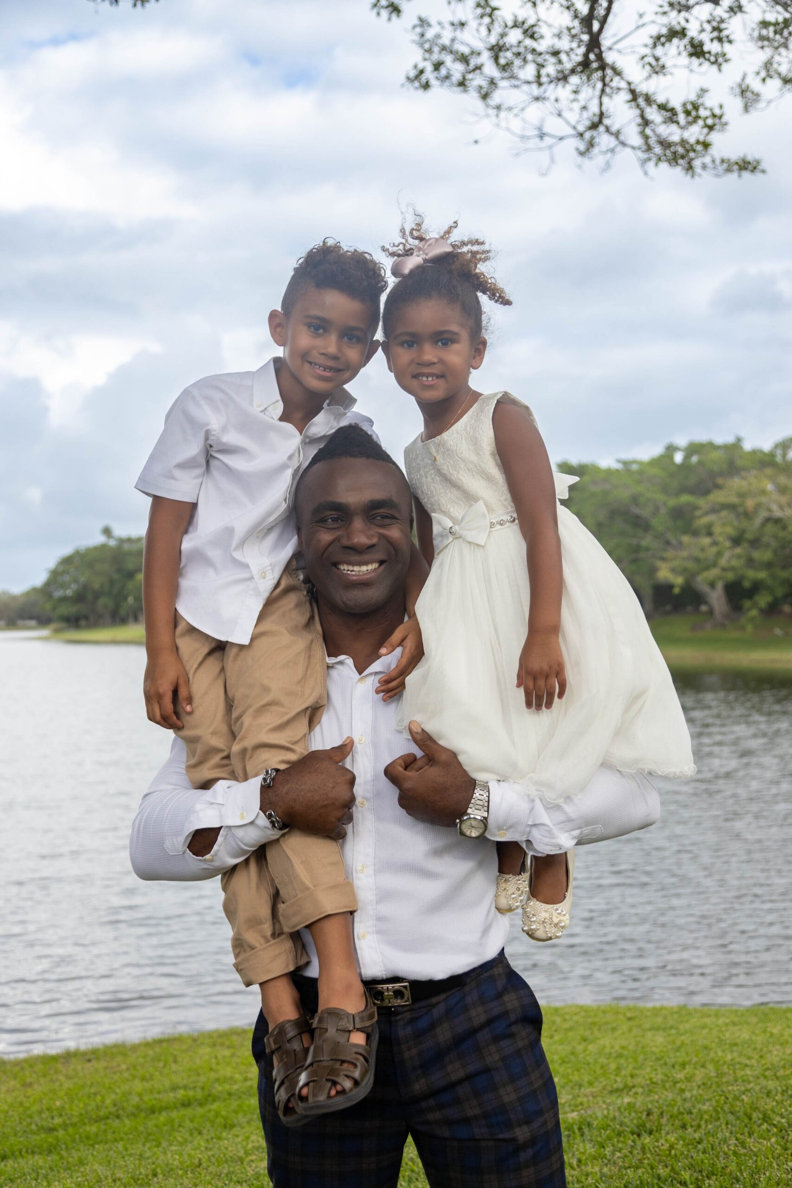 Father carrying his two children on his shoulders by the lake in Palm Beach County