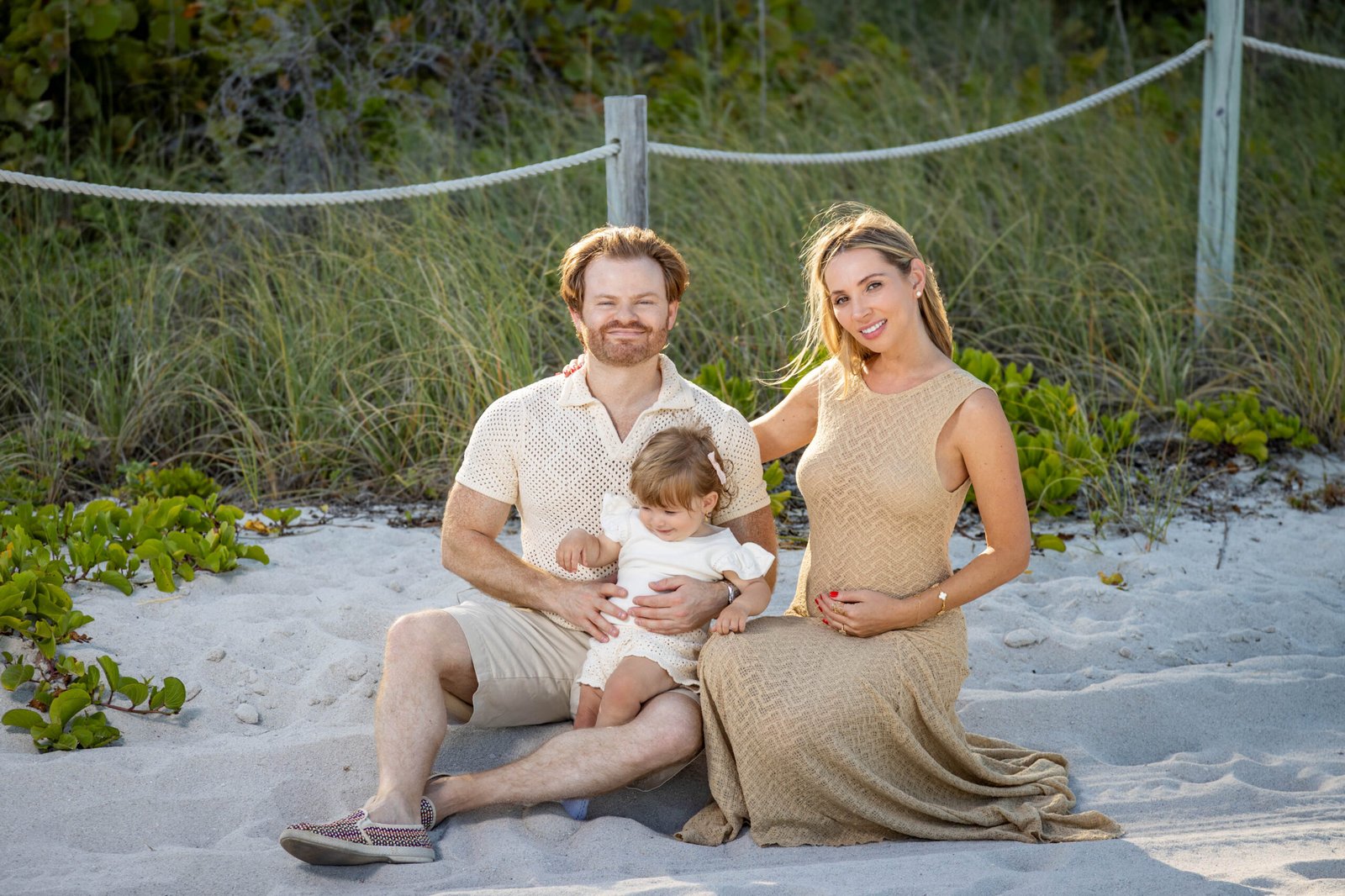 Expectant family embracing in the beach dunes during a West Palm Beach maternity photo session