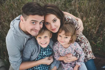 Happy family portrait with father, mother and two young children smiling outdoors