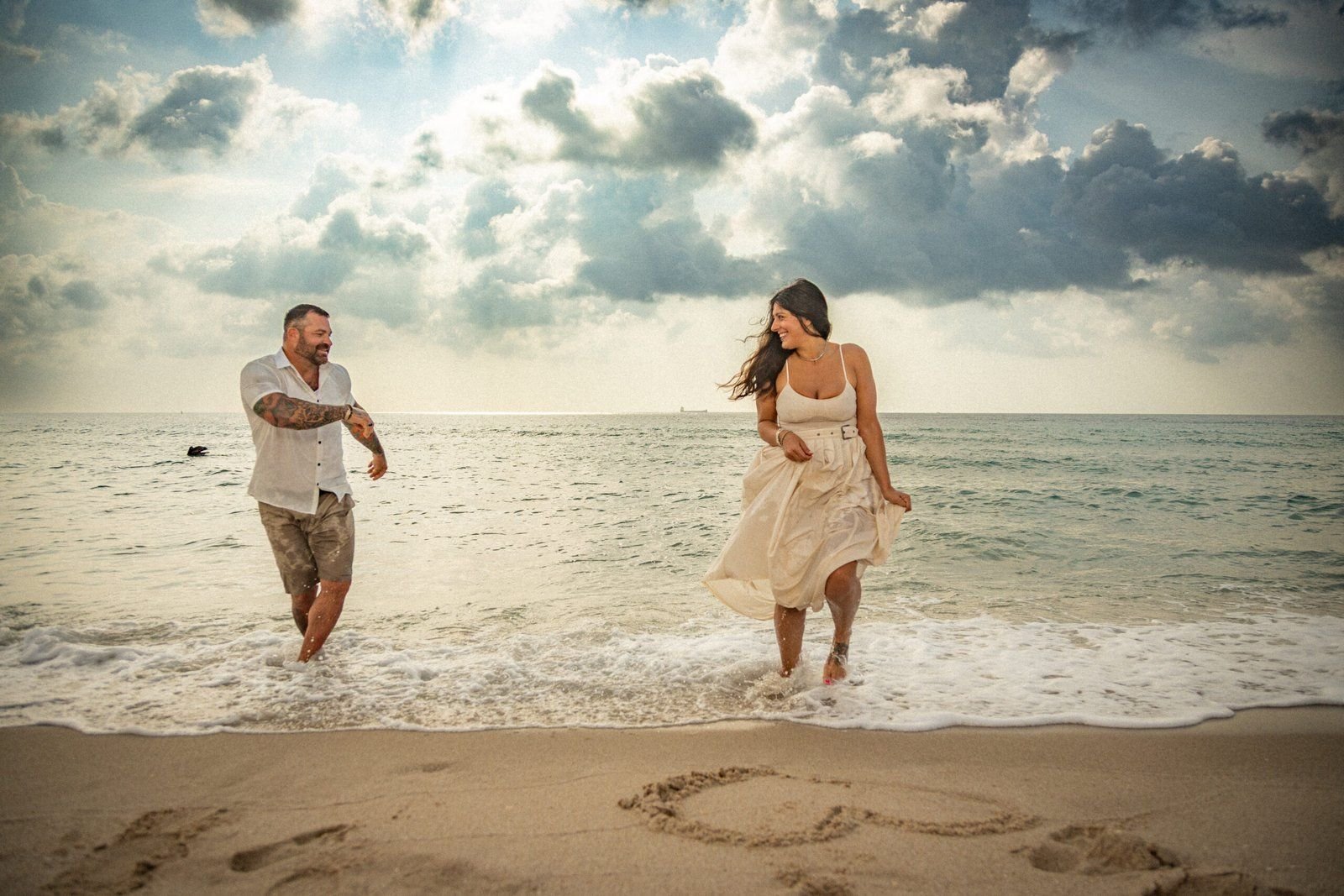 Pareja comprometida corriendo en la playa de West Palm Beach al atardecer