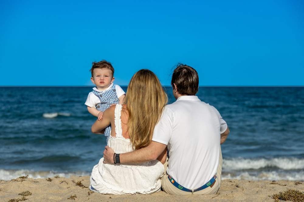 Familia mirando el océano con su hijo pequeño al atardecer