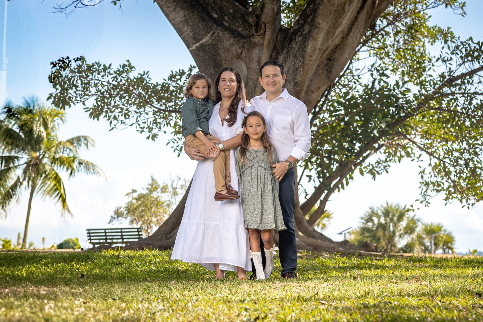 Happy family portrait session outdoors under a large banyan tree in the park