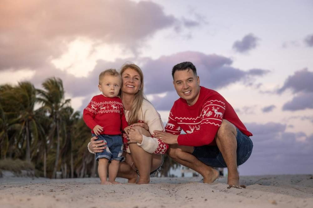 Familia posando junta en atuendos coordinados en una sesión de playa al atardecer