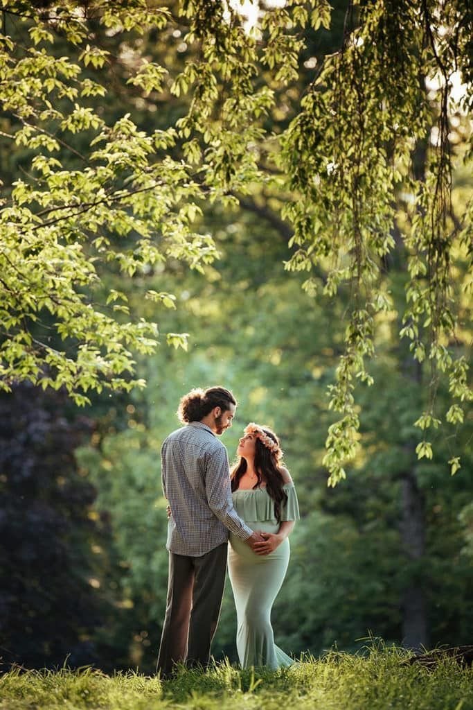 Expecting parents photographed under trees during a maternity session