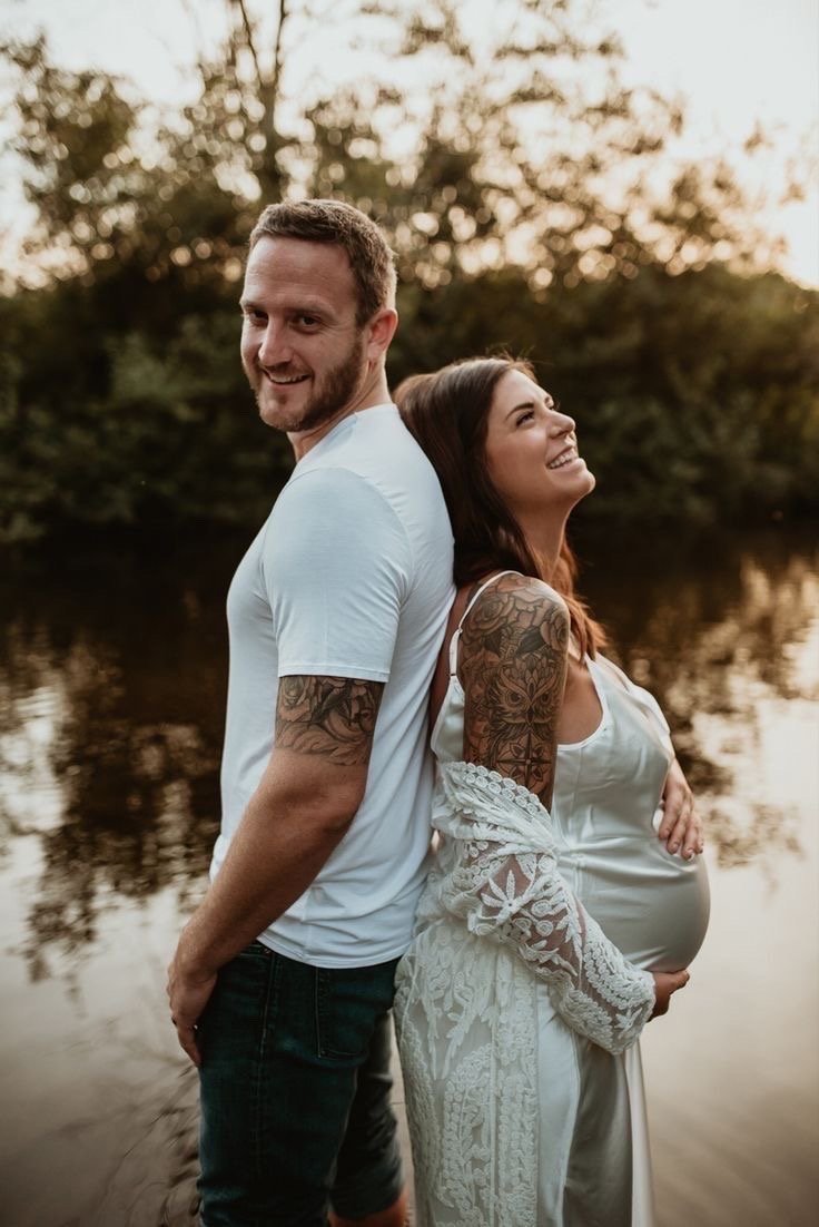 Expecting parents photographed by the water at golden hour