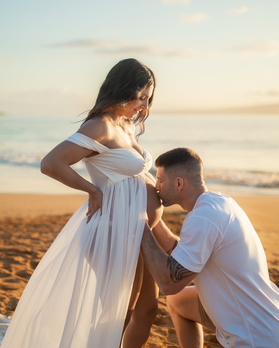 Partner kissing the bump during a beach maternity session at sunset in South Florida