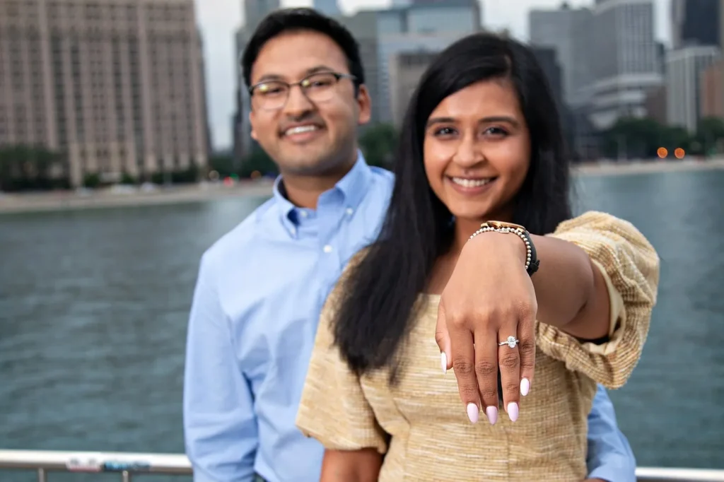 Bride-to-be showing her engagement ring with the Chicago skyline softly blurred behind at golden-hour sunset