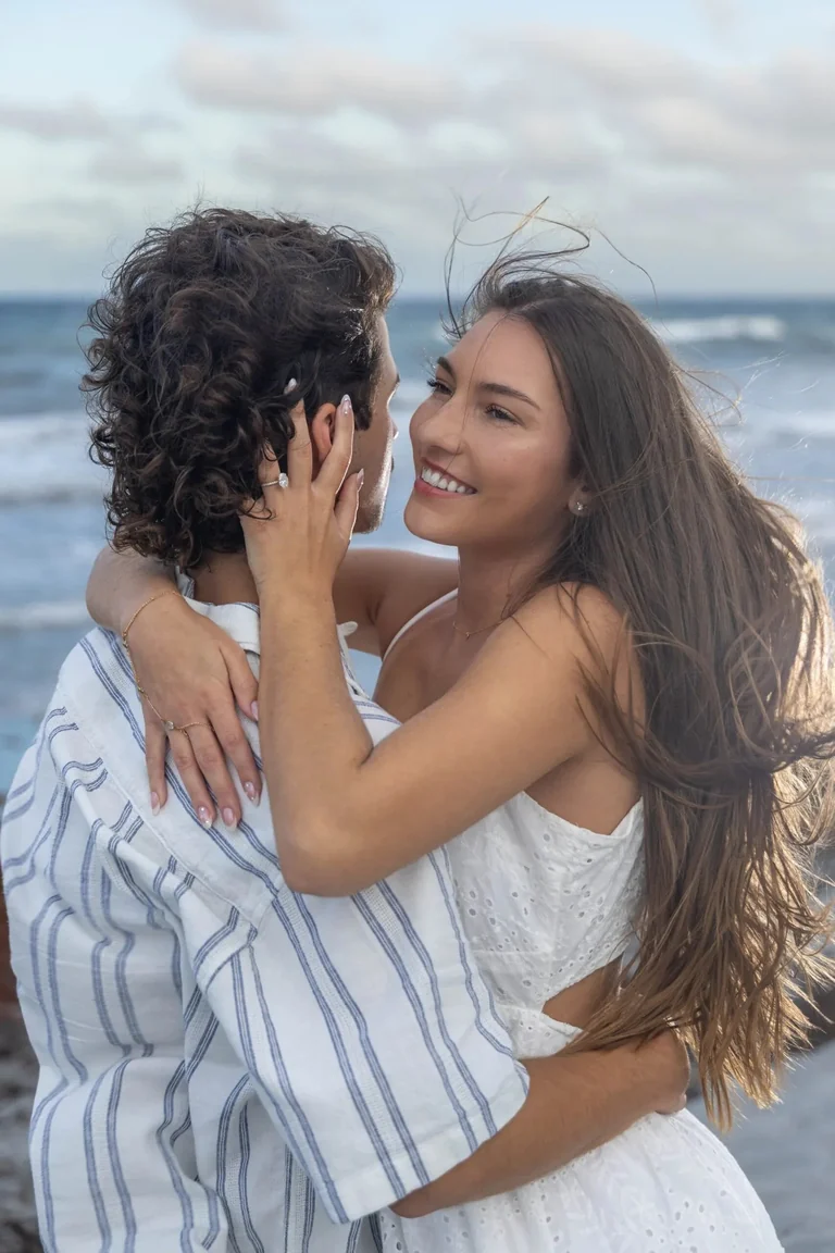 Romantic couple embrace on beach wind in hair West Palm Beach engagement photographer intimate moment
