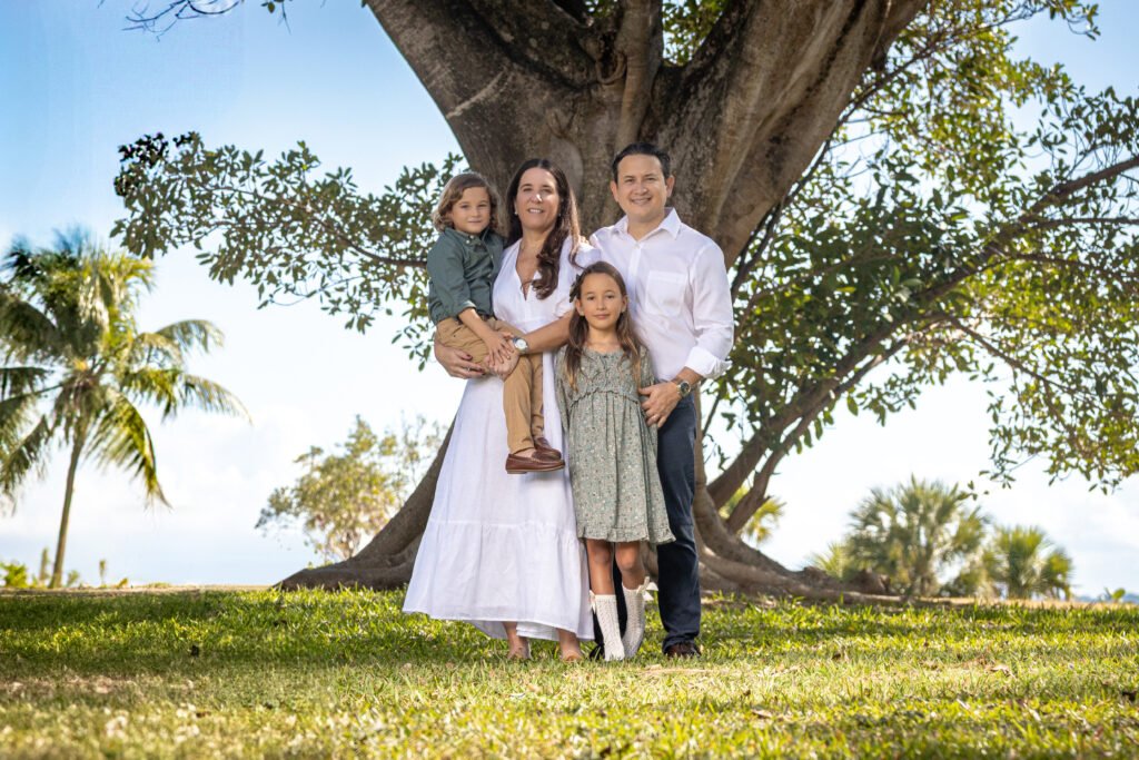 Family of four under a large banyan tree at a park in Wellington, FL, family photo session by The Love Pics