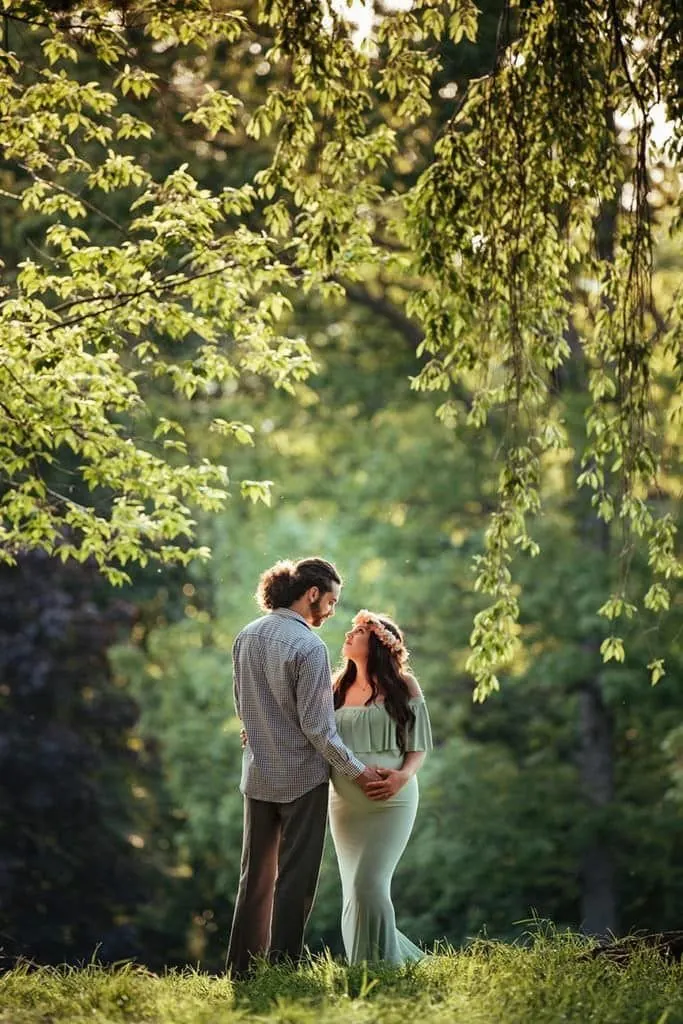 Expecting parents photographed under trees during a maternity session