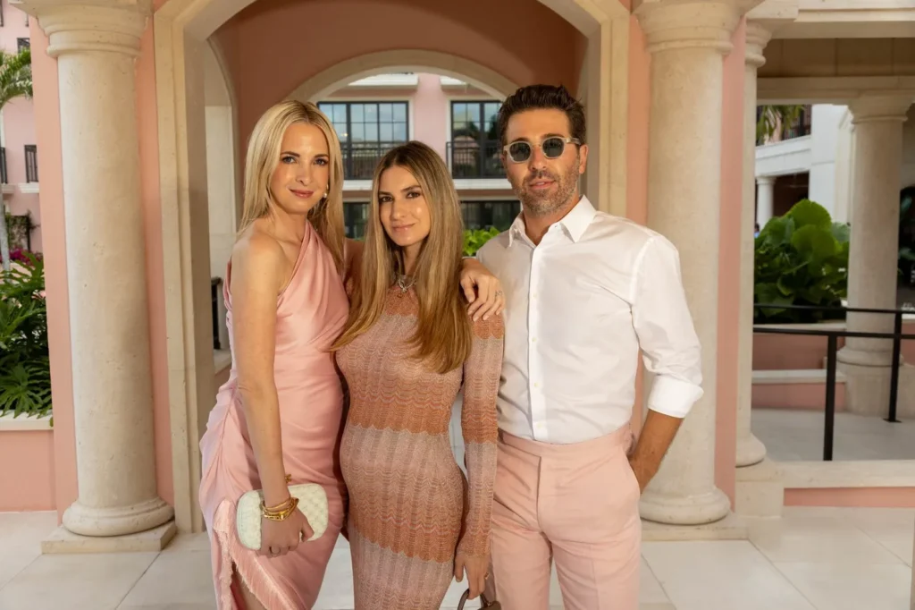 Familia elegante con tonos rosados posando frente a edificio de columnas mediterráneo