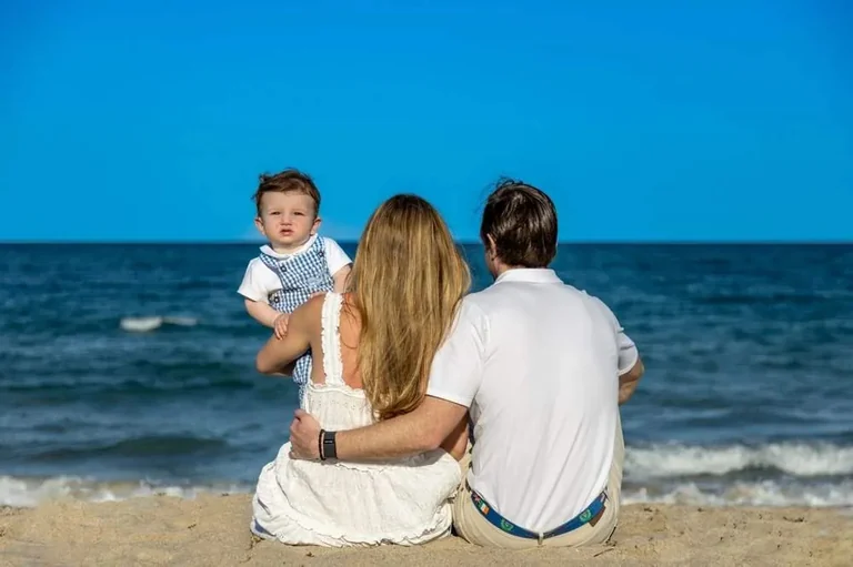 Family looking out at the ocean with their toddler son at sunset