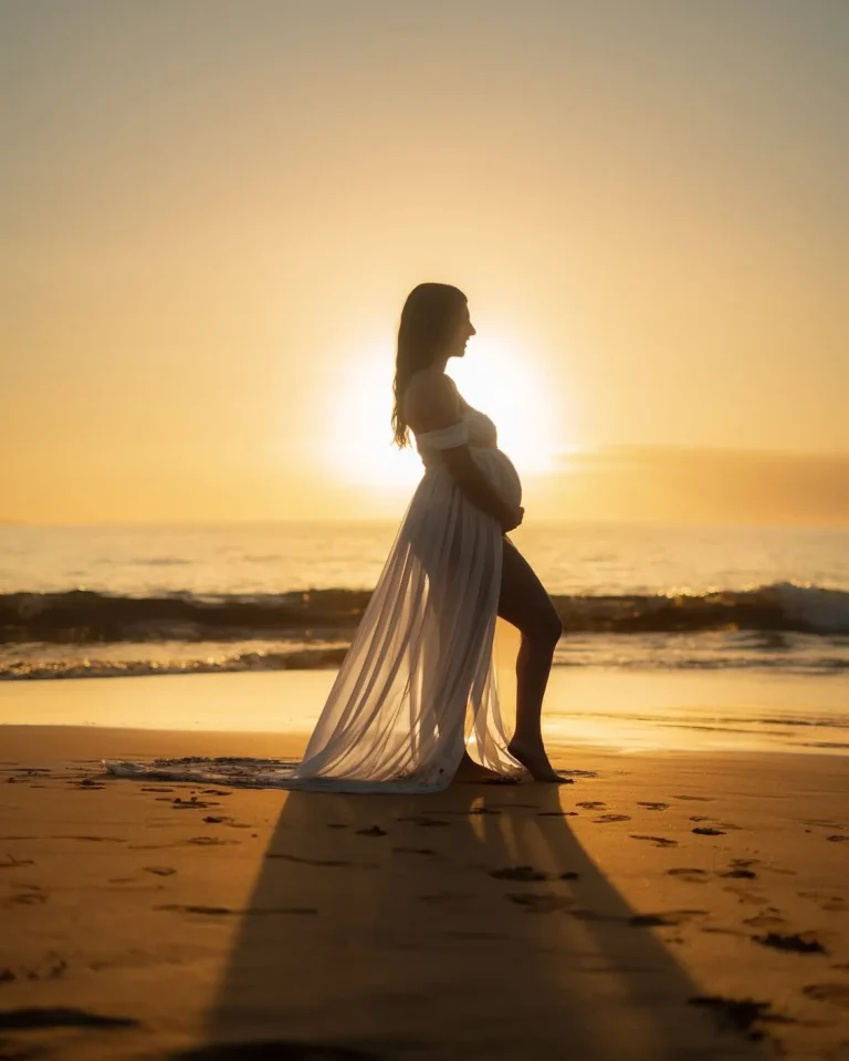 Silhouette of a pregnant woman in a flowing dress on the beach at sunrise, maternity photos in South Florida
