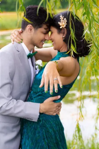 Pareja de novios romántica abrazándose bajo ramas de sauce en su boda