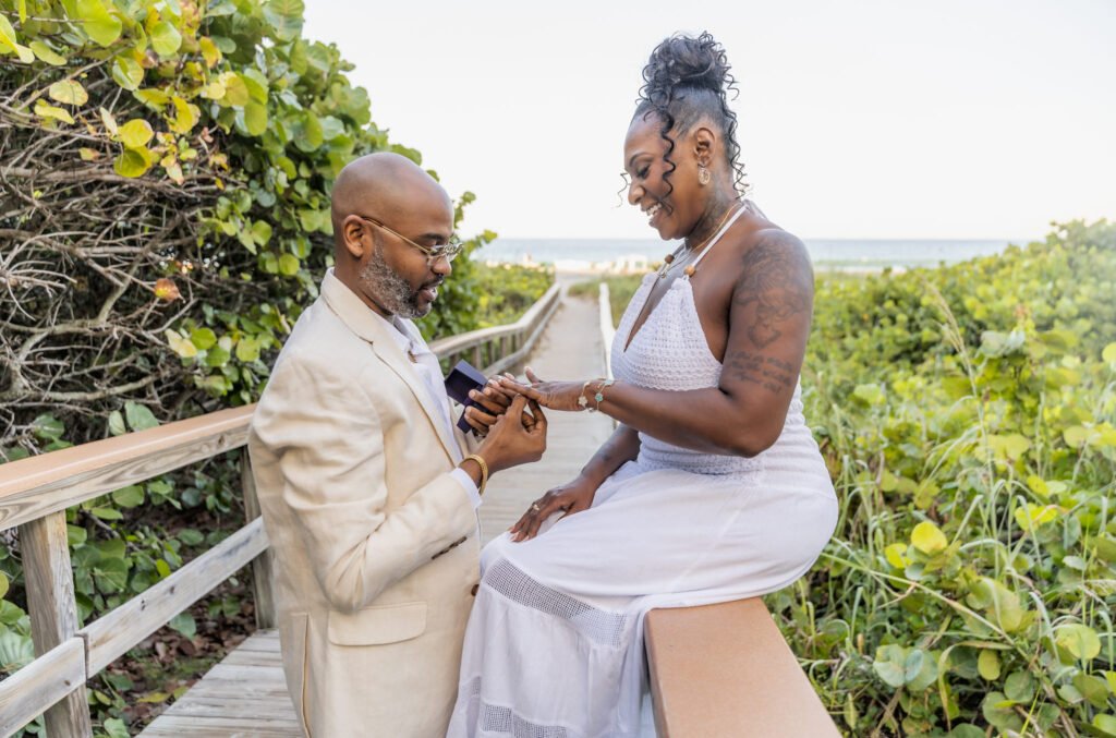 He slips the ring on Katherine's finger as she sits on the railing of a beach boardwalk lined with sea grapes in Boynton Beach