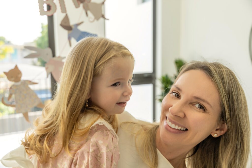 Mother smiling with her young daughter at home during a family session in Palm Beach County